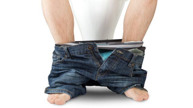 Man sitting on a toilet seat with his pants and boxers down