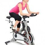 young woman doing indoor biking exercise, on white background