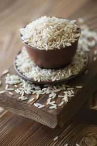 Raw brown rice over rustic wooden background, close-up