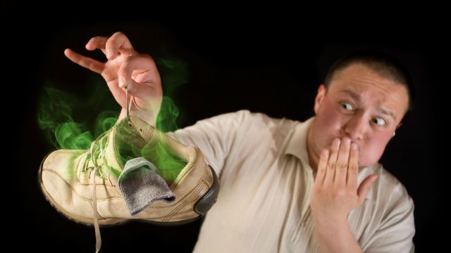 Shocked man holding smelling shoe
