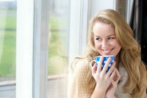 Smiling young lady holding cup of tea