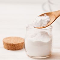 sea salt, starch in the jar and wooden spoon for recipes of cosmetics at home on a white wooden background