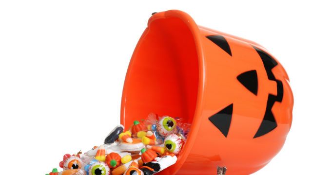 child halloween pumpkin bucket spilling candy
