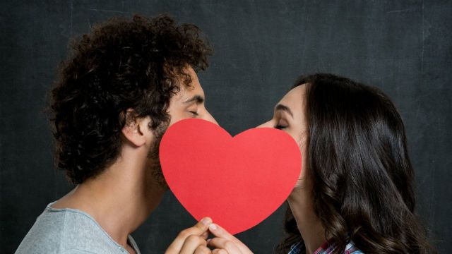 Couple Kissing Behind Paper Heart