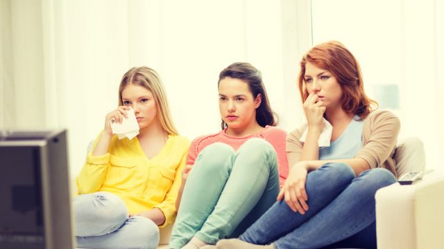 three sad teenage girl watching tv at home