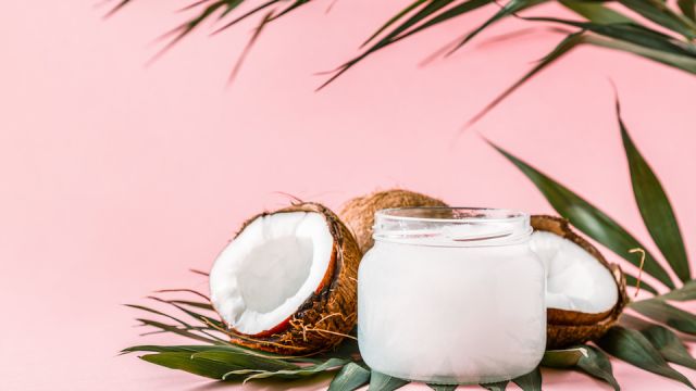 Coconut oil and coconuts on a bright pastel background.