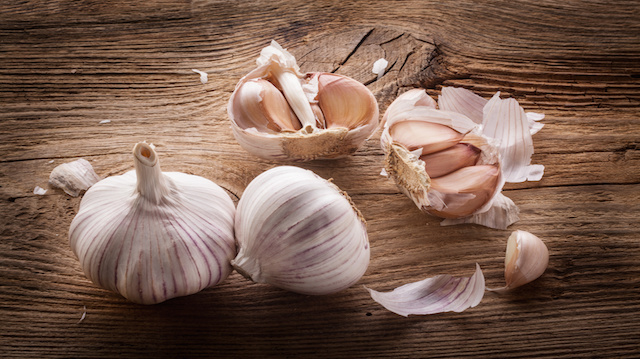 Garlic bulbs and cloves on wooden table, closeup