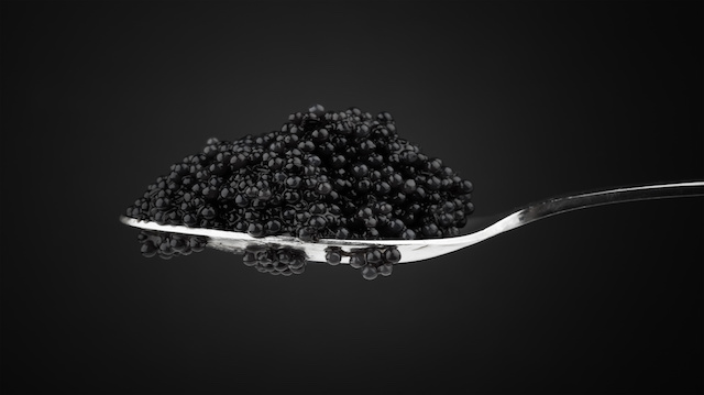 Black caviar in metal teaspoon. Macro photo on dark background