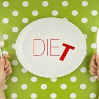 Hands hold flatware above dieting plate