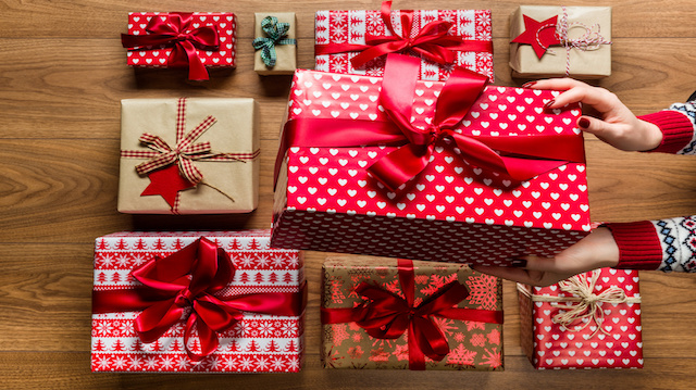 Woman organising beautifuly wrapped vintage christmas presents on wooden background, view from above