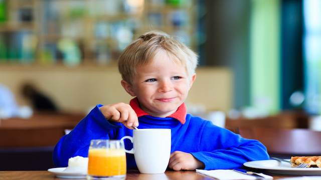 little boy eating breakfast in cafe