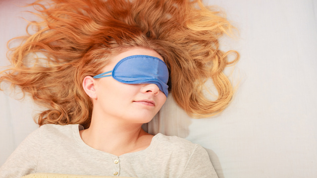 Sleeping woman wearing blindfold sleep mask.