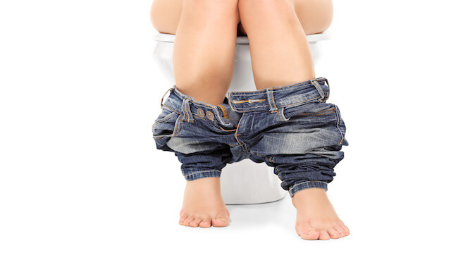 Female seated at a toilet with her pants down