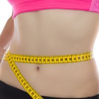 Fit woman measuring her waistline with a tape