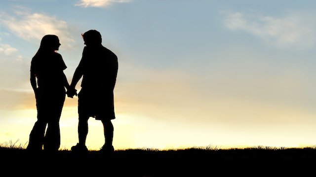 Silhouette of Happy Couple Holding Hands and Talking at Sunset