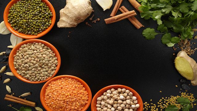 Bowls with legumes and indian spices, fresh and dried on black background, copy space