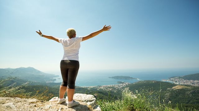 Woman with raised up hands enjoying sunny day
