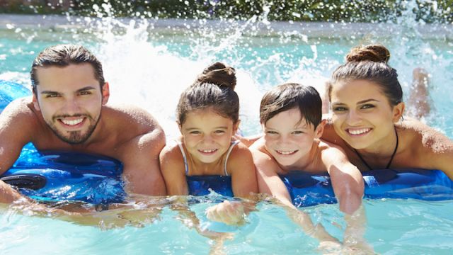 Portrait Of Family On Airbed In Swimming Pool