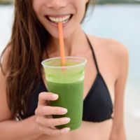 Green smoothie – woman holding detox juice in sun