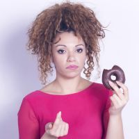 Funny woman eating donut feeling guilty.