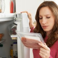Concerned Woman Looking At Pre Packaged Meat