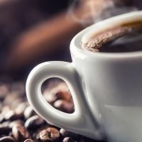 Cup of black coffee with beans on wooden table