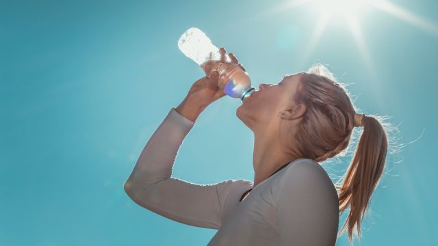 Blonde, sporty woman drinking water after her training in the morning.